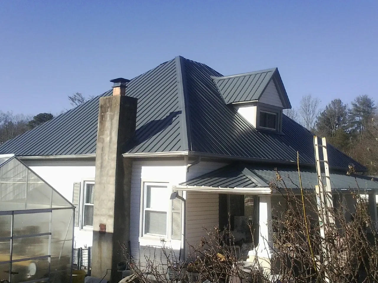 Dark blue standing seam metal roof on a white farmhouse with dormer — Slate & Tile Roof Repair by Roofing Brothers in North Aurora