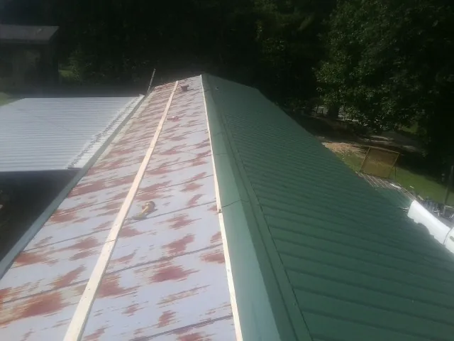 Old rusted panels beside newly installed green metal roofing — Wind Damage Roof Repair by Roofing Brothers in North Aurora