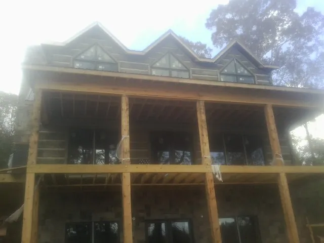 Dormers and porch framing on a large log home under construction — Roof Coating work by our crew in North Aurora
