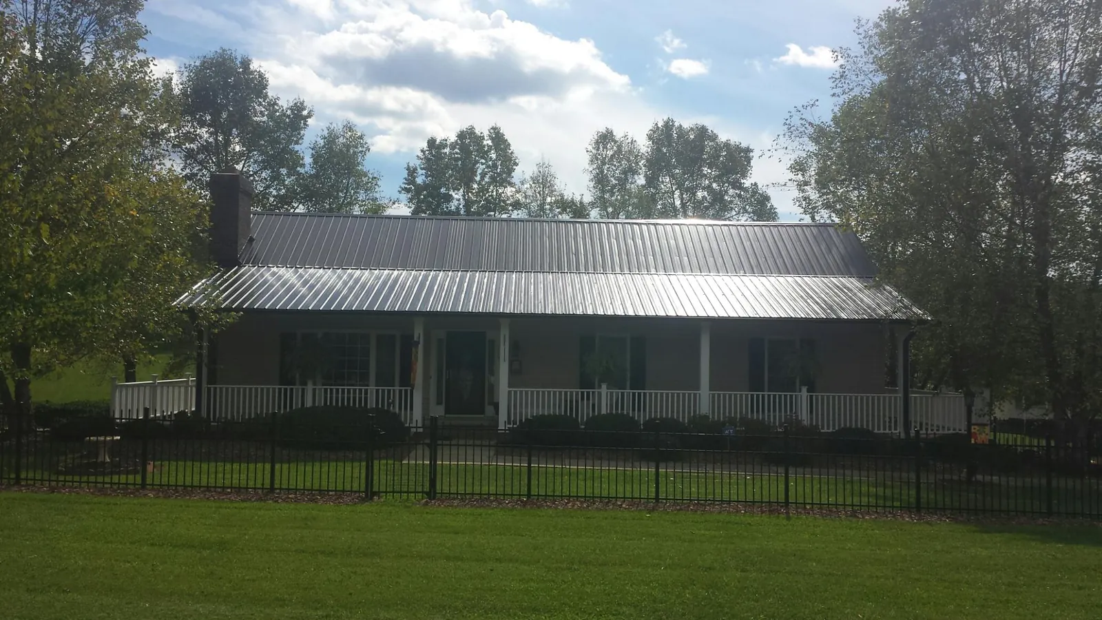 Gray metal roof on a brick ranch with a full width front porch — Gutter Guard Installation work by our crew in North Aurora