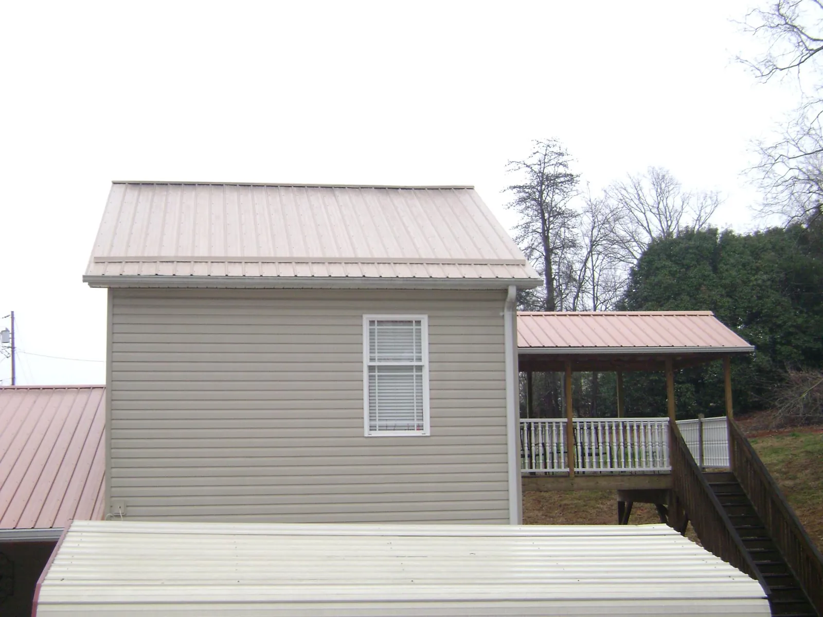 Tan metal roofs on a two story addition and attached porch, from a Roof Replacement job in North Aurora