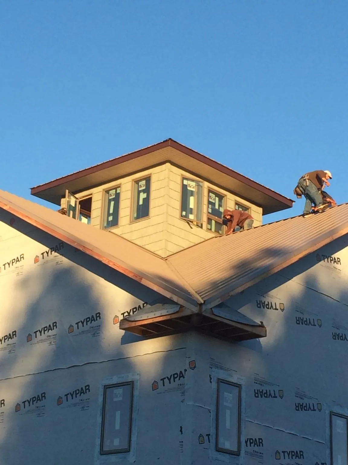 Roofers working around a rooftop cupola on a new metal roof at sunset — Roof Waterproofing in North Aurora by Roofing Brothers